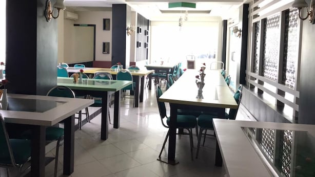 A spacious dining area with multiple tables and chairs, a chandelier, and a view of the outdoors. - Grand Balqis Akasia Hotel (Surabaya)