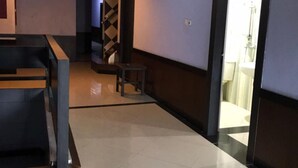 A hotel lobby with a reception desk, a staircase, and a door leading to a bathroom. - Grand Balqis Akasia Hotel (Surabaya)