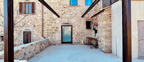 Un edificio de piedra con un patio de grava, una puerta de madera y un portón de metal.