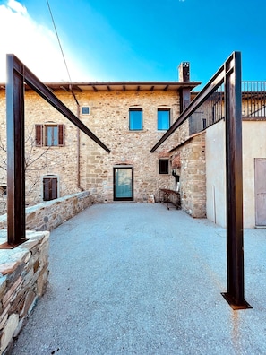 A stone building with a gravel courtyard, a wooden door, and a metal gate.
