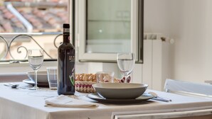 Una mesa de comedor preparada con una botella de vino, copas, un bol y una cesta de pan.