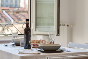 Ett matbord dukat med en vinflaska, glas, en skål och en korg med bröd.