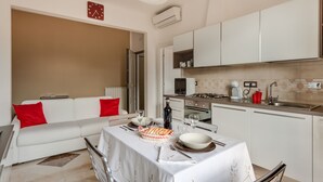 Una cocina moderna con armarios blancos, una mesa de comedor lista con platos, vasos y una botella.