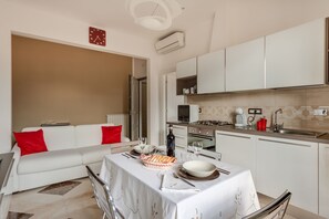 A modern kitchen with white cabinets, a dining table set with plates, glasses, and a bottle.