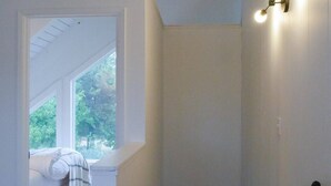 Un intérieur moderne avec un escalier, un lit et une fenêtre donnant sur un paysage verdoyant.