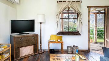 Een gezellige woonkamer met een televisie, een houten kast, een lamp en een raam met gordijnen.