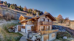 Een houten chalet met een balkon, stenen trappen en uitzicht op het omliggende bos.