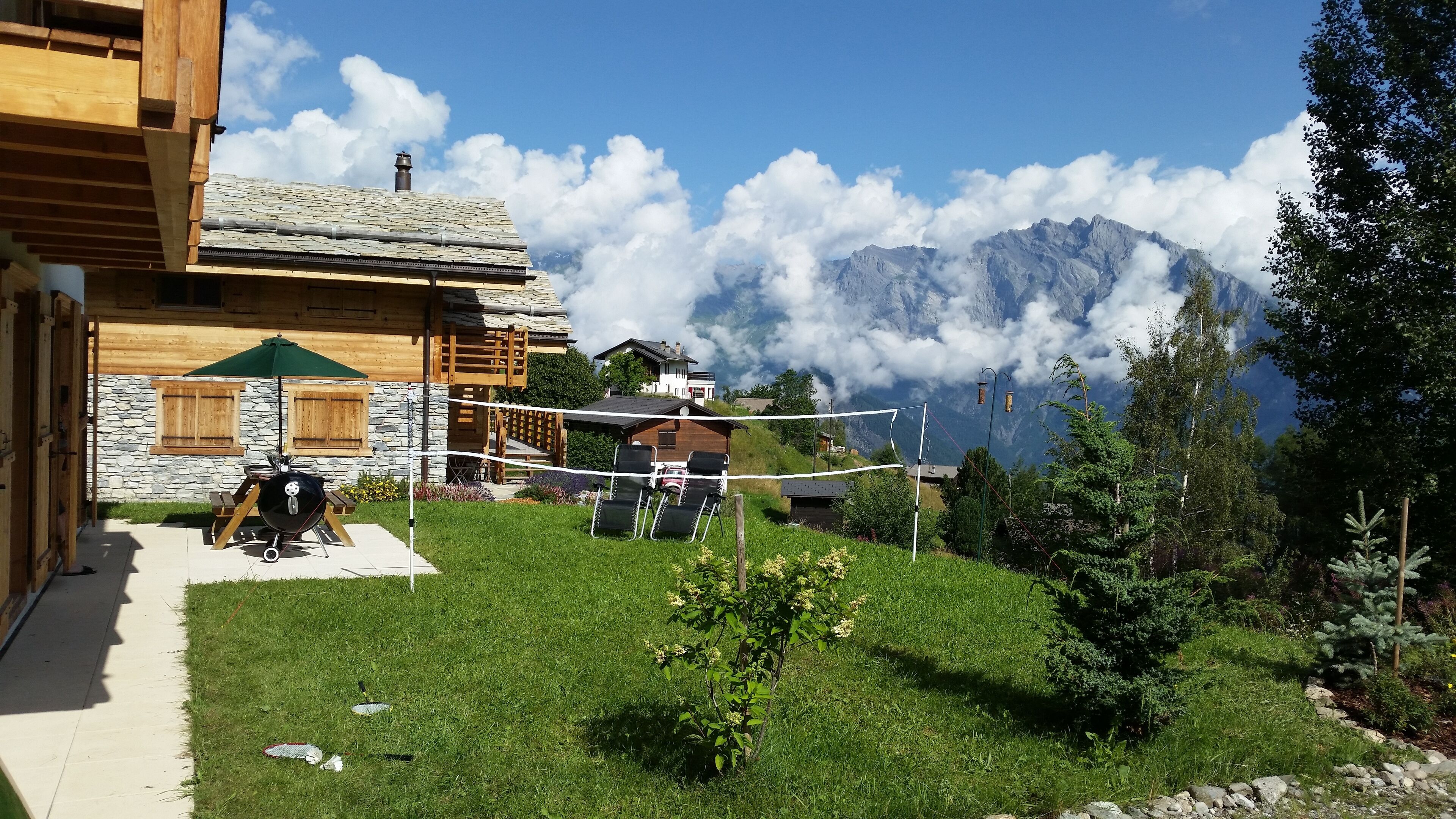 Une cabane en bois avec un mur en pierre, un barbecue et une vue sur les montagnes.