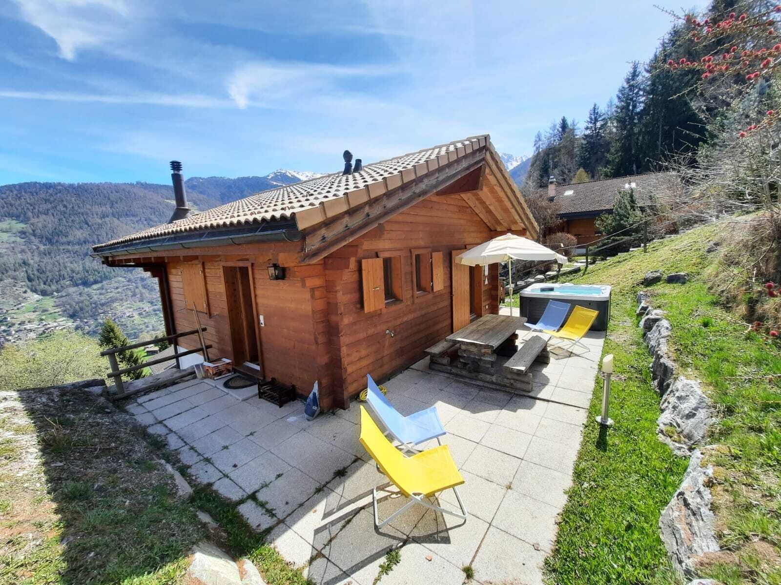 Une cabane en bois avec un toit en tuiles, un jacuzzi et un espace salon extérieur.
