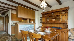 Une table de salle à manger en bois, dressée avec des assiettes et des verres, entourée de chaises en bois dotées de sièges rembourrés.