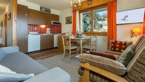 Een knus woongedeelte met kitchenette, een eethoek en een zithoek met een bank en fauteuil.