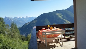 Een tafel buiten opstelling met uitzicht op een berg, een stoel en een tafelkleed.