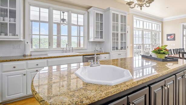 A kitchen with white cabinetry, a granite countertop, a white sink, and a chandelier. - LakeViews, Indoor/Outdoor Pools, HotTub & Fire Pit (Branson)