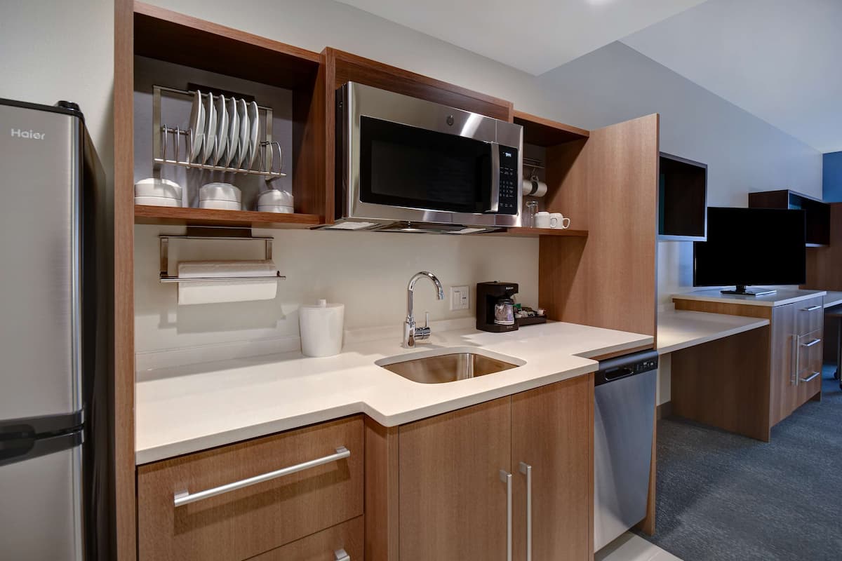 A modern kitchen with a stainless steel refrigerator, a microwave, a coffee maker, and a dishwasher.