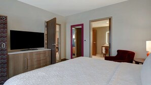 Ein Hotelzimmer mit Bett, Fernseher, Schreibtisch und Stuhl.