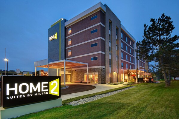 Un hôtel à plusieurs étages, reconnaissable à son grand panneau indiquant « HOME 2 Suites by Hilton ».