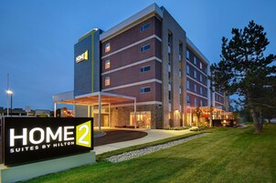 Un hotel de varios pisos con un letrero destacado que dice "HOME 2 Suites by Hilton".