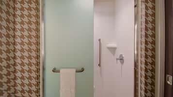 Une salle de bain avec une douche, un porte-serviettes avec une serviette, et un papier peint à motifs.