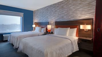 A hotel room with two beds, a large window, and a textured wall.