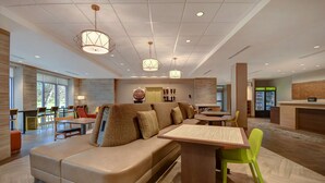 Eine moderne Hotelhalle mit Sitzgelegenheit, einer Rezeption und einem Verkaufsautomaten.