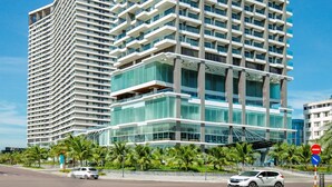 A modern high-rise building with multiple balconies, large windows, and a glass facade. - FLC City Hotel Beach Quy Nhon (Quy Nhon Nam)