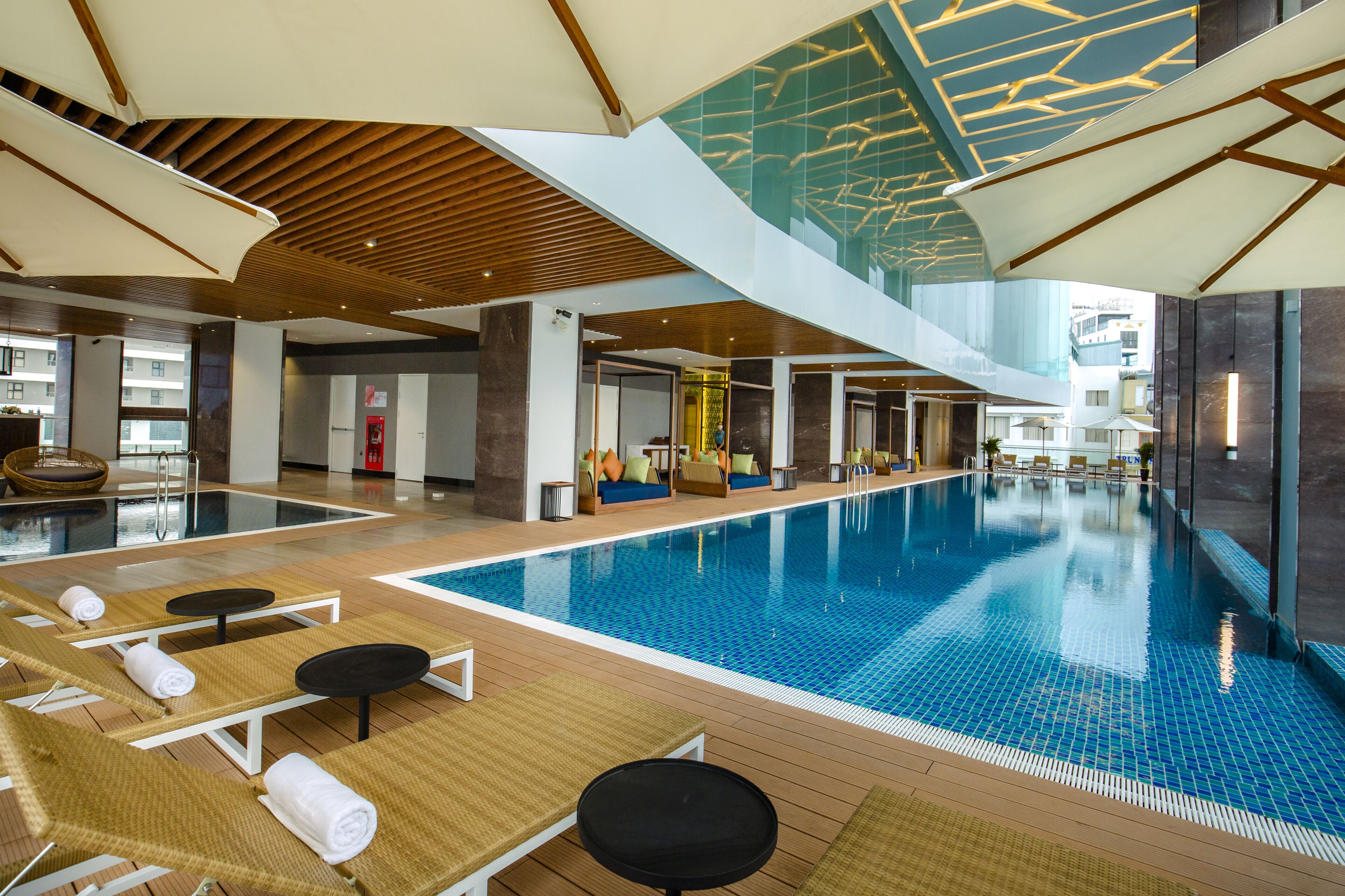 An indoor swimming pool with lounge chairs and a modern ceiling design.