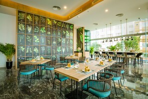 Enjoy meals in this stylish dining area with a long table and wicker chairs, surrounded by nature-inspired artwork.