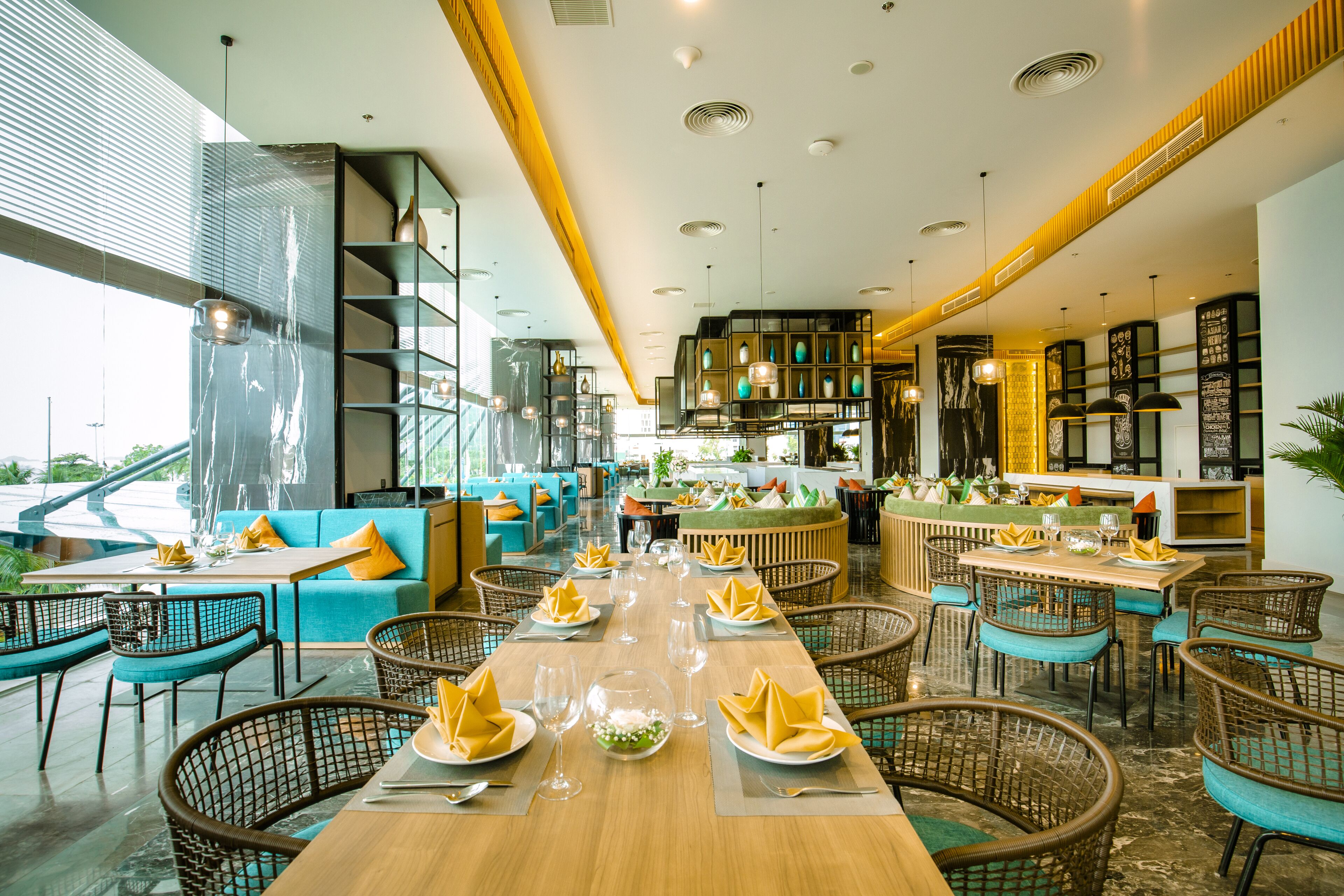 Een ruim restaurant met hoge plafonds, moderne verlichting en een combinatie van zitplaatsen, zoals tafels en stoelen.