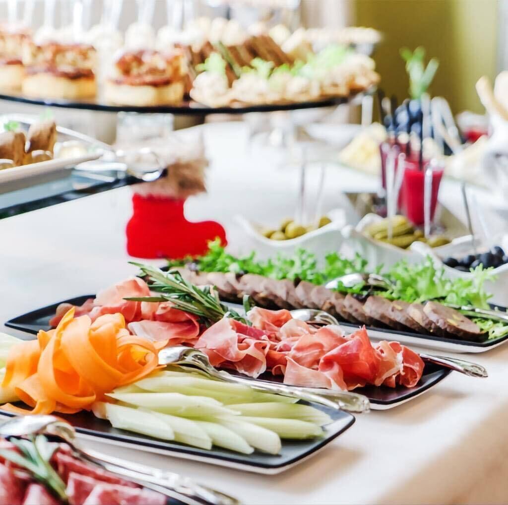 A buffet table with various food items including meats, cheeses, and garnishes.