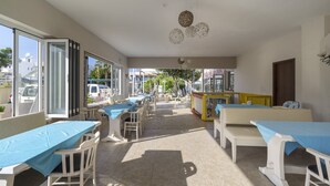 A restaurant with outdoor seating, white tables, and blue tablecloths. - Anemi Hotel (Hersonissos)