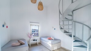 A modern room with two beds, a white bench, a window, and a spiral staircase. - Anemi Hotel (Hersonissos)