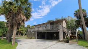 A two-story building with a covered parking area, palm trees, and a clear sky.