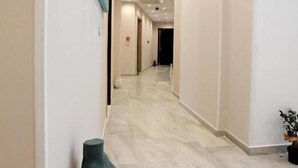 A hallway with a marble floor, a sculpture, and a red object on the wall. - Afrodite Suites (Sarandë)