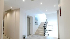 A modern interior with a staircase, white walls, and a potted plant. - Afrodite Suites (Sarandë)