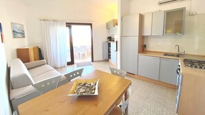 Un espacio habitable compacto con comedor, kitchenette y sofá.