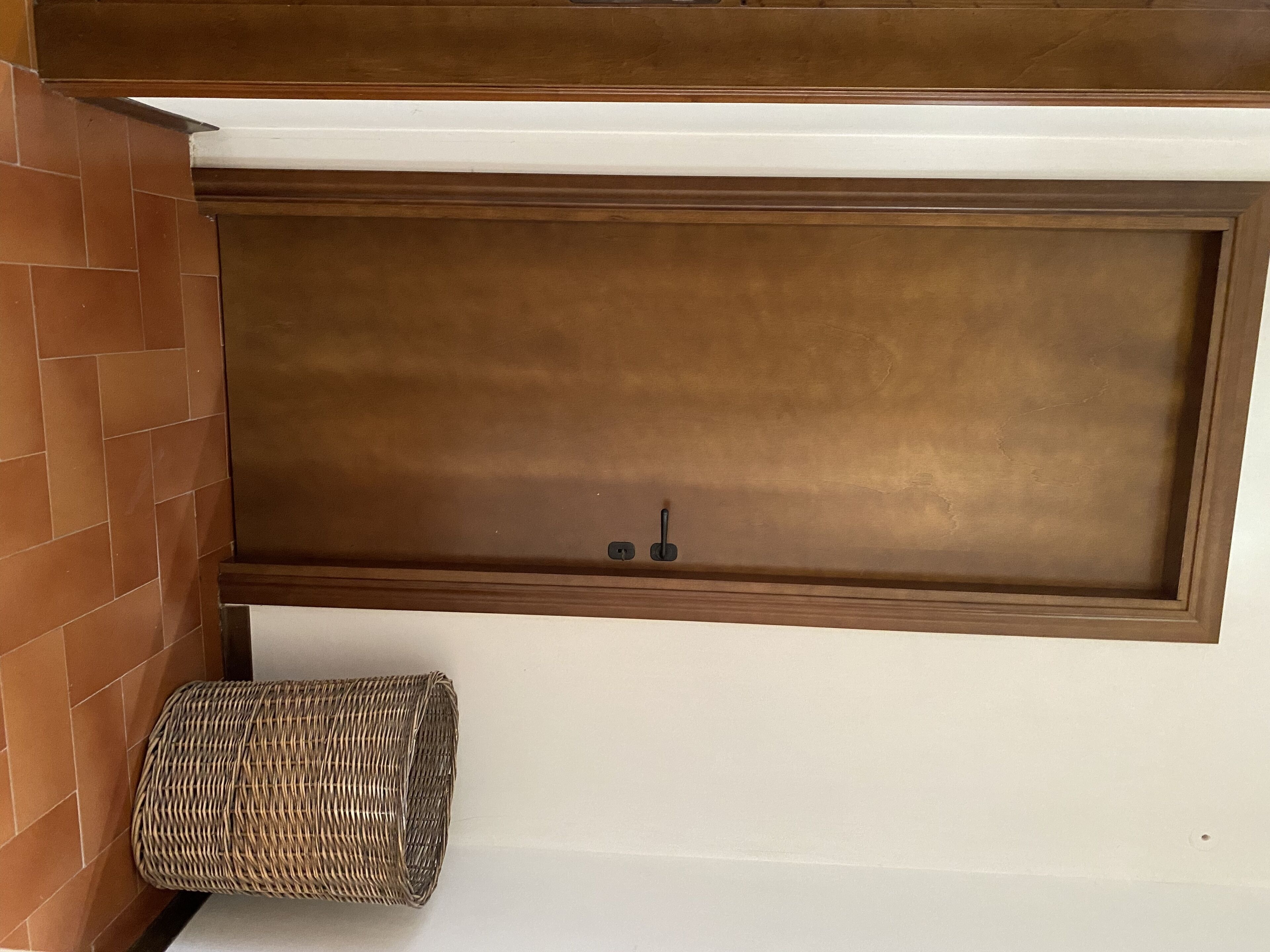 A bathroom with a wooden vanity, a white sink, and a wicker stool.