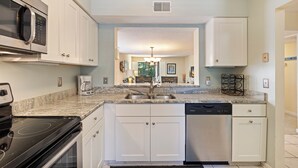 A kitchen with white cabinets, a stainless steel microwave, a dishwasher, and a granite countertop.
