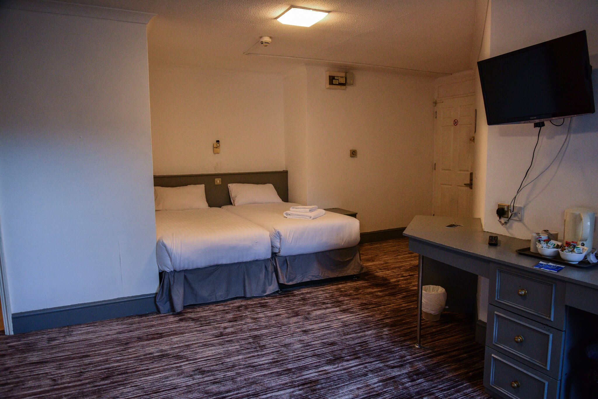 Een hotelkamer met een bed, een bureau, een televisie en een badkamer.