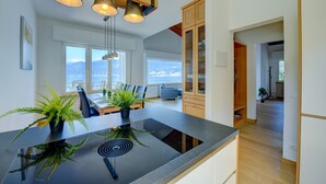 A modern kitchen with a central island, wooden cabinets, and pendant lighting. - Casa Bellavista Brenzone (Brenzone)