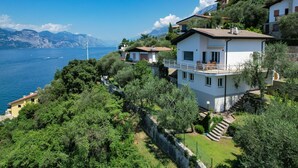 A coastal house with a balcony overlooking the sea, surrounded by lush greenery and mountains in the background. - Casa Bellavista Brenzone (Brenzone)