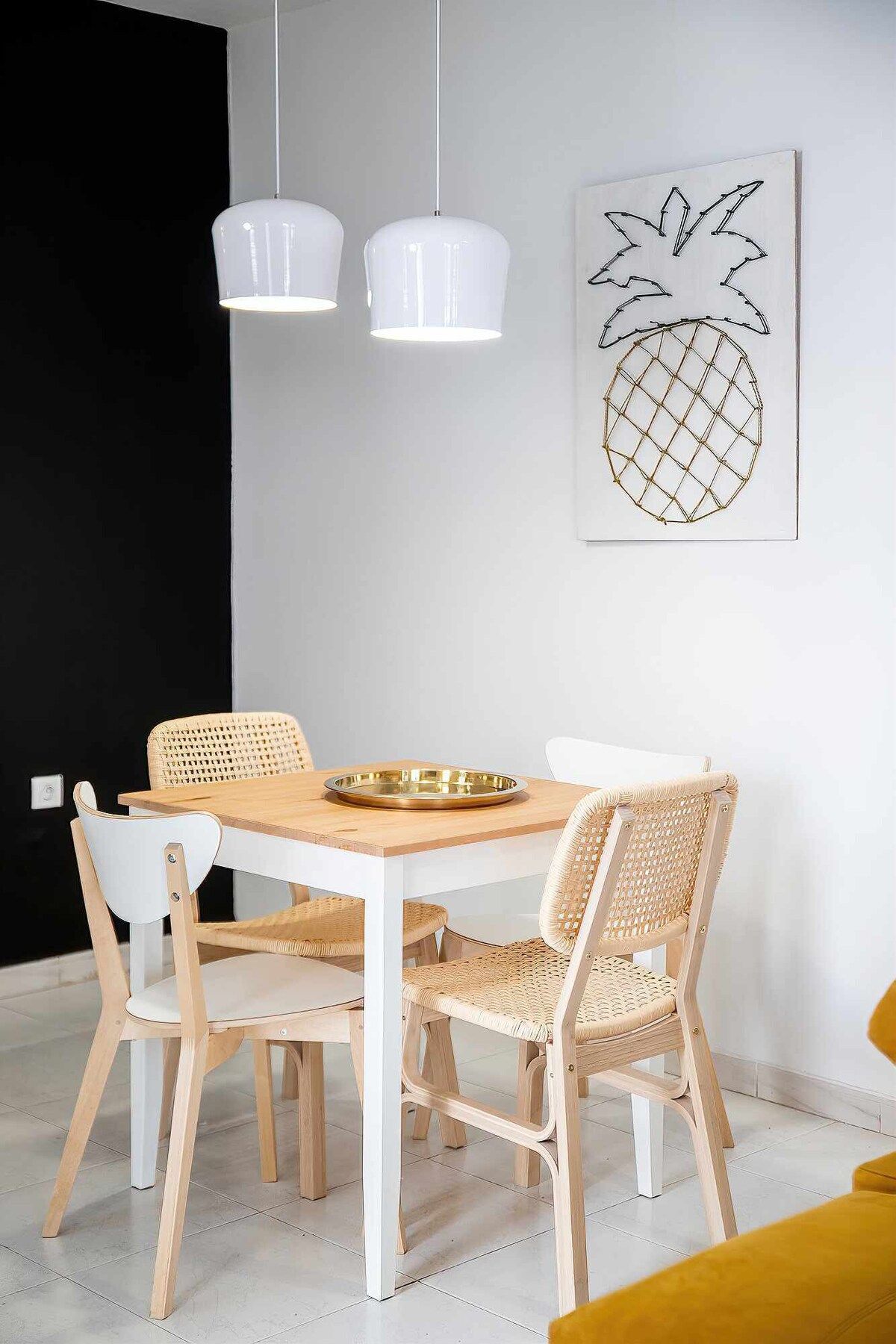 Uma área de refeições com uma mesa redonda, quatro cadeiras e duas luminárias pendentes.