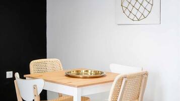 Uma área de refeições com uma mesa redonda, quatro cadeiras e duas luminárias pendentes.