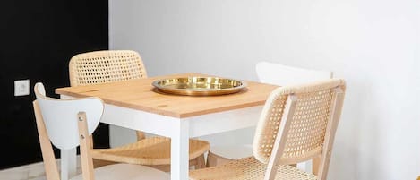 Un comedor con una mesa redonda, cuatro sillas y dos lámparas colgantes.