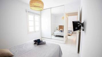 Une chambre d’hôtel équipée d’un lit, d’un grand miroir, d’une armoire et d’un téléviseur fixé au mur.