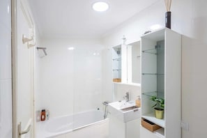 Un baño moderno con ducha acristalada, lavamanos blanco y un mueble de espejo.