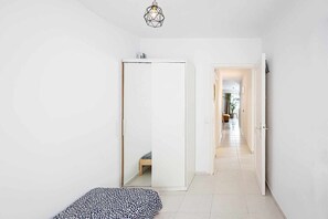 A hallway with a mirrored wardrobe, a small bench, and a door leading to another room.