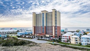 A multi-story hotel with a central courtyard and a view of the beach. - Corner Condo w/ Panoramic Views of the Gulf & Lagoon | Pool & Sauna | Sleeps 10 (Gulf Shores)