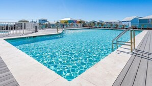 A rectangular swimming pool with clear blue water, surrounded by a wooden deck and a white fence. - Corner Condo w/ Panoramic Views of the Gulf & Lagoon | Pool & Sauna | Sleeps 10 (Gulf Shores)
