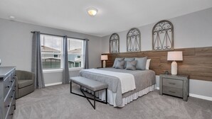 Ein Schlafzimmer mit Bett, Bank, Schminktisch, Nachttisch und dekorativen Wandverkleidungen.