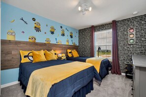 A bedroom with two beds, a brick wall, a Minion-themed mural, and a desk with drawers.